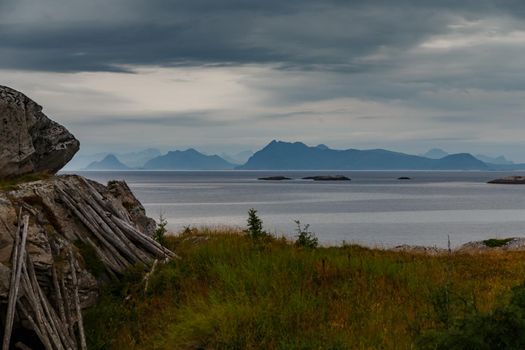 Norwegian seascape, rocky coast with dramatic skies, the sun breaks through the clouds, sheer cliffs, small islands illuminated by the sun. High quality photo