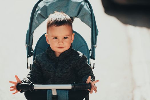 Sweet baby boy tow years old in a stroller bicycle outdoors. Little child in a pram. Infant kid in a pushchair. Spring walks with kids. High quality photo