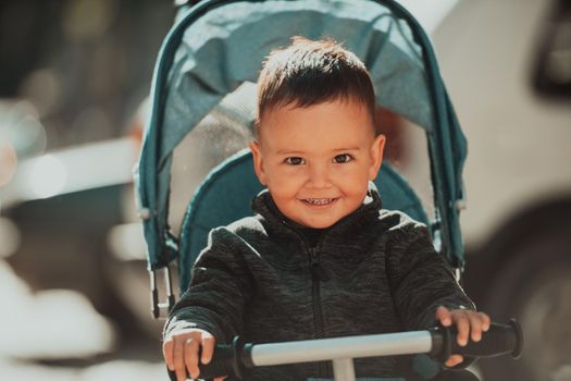 Sweet baby boy tow years old in a stroller bicycle outdoors. Little child in a pram. Infant kid in a pushchair. Spring walks with kids. High quality photo