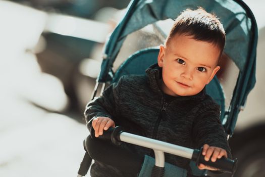 Sweet baby boy tow years old in a stroller bicycle outdoors. Little child in a pram. Infant kid in a pushchair. Spring walks with kids. High quality photo