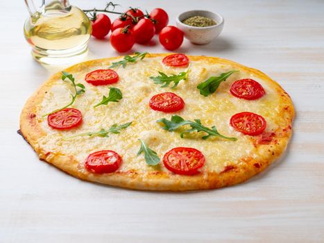 hot homemade Italian pizza margherita with mozzarella and tomatoes on white wooden table, side view.