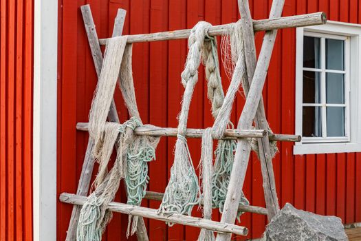 Lofoten islands, fishing nets hanging on the fence or porch, classic Norwegian landscape, house of red color, fishnets carefully picked. High quality photo