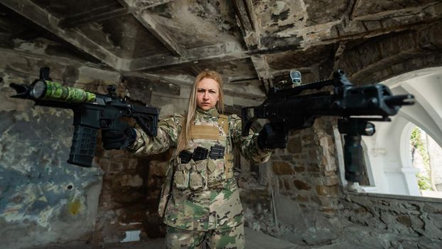 Caucasian woman in army uniform holding two machine guns