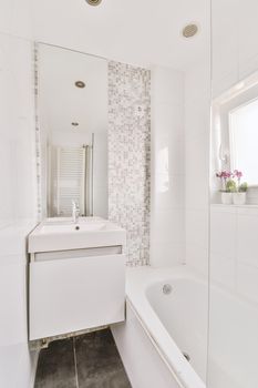 Modern home interior design of white bathroom with bathtub separated from sink and mirror by partition glass wall