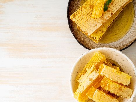 honey in honeycomb, close-up, on brown ceramic plate, on white wooden rustic table, top view, copy space.