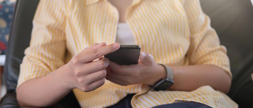 Close up woman holding and using mobile phone.