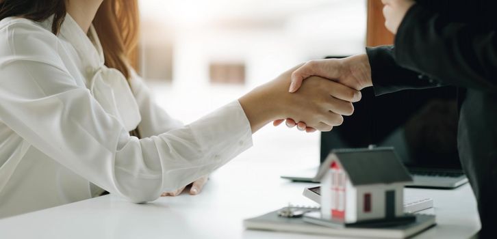 Two business people shaking hands as successful agreement in real estate agency office. Concept of housing purchase and insurance..