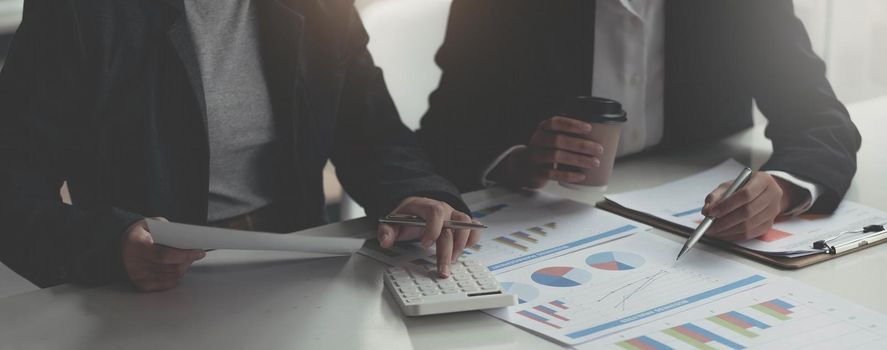 Business analyst pointing to earnings charts and graphs. Analysts are calculating the numbers with a calculator for good future earnings.