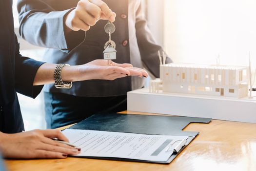 estate agent giving house keys to man and sign agreement in office.