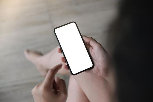 Woman hand holding smartphone with blur bokeh. Blank white screen mobile phone for graphic display montage.
