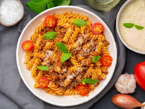 Bolognese pasta. Fusilli with tomato sauce, ground minced beef, basil leaves. Traditional italian cuisine. Top view.