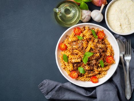 Bolognese pasta. Fusilli with tomato sauce, ground minced beef, basil leaves. Traditional italian cuisine. Top view, copy space