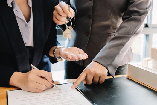 estate agent giving house keys to man and sign agreement in office.