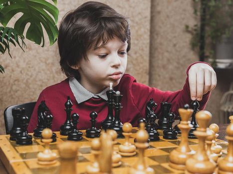 Smart Caucasian kid making a move in the chess game. Children educational leisure activities