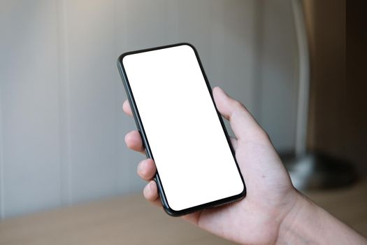 Woman hand holding smartphone with blank white screen.