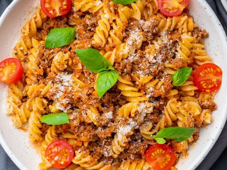 Bolognese pasta. Fusilli with tomato sauce, ground minced beef, basil leaves. Traditional italian cuisine. Top view, close up.