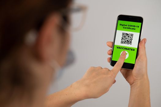 The doctor holds a smartphone with a QR code about the vaccination performed