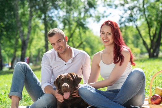 A couple and their dog in the park. Spending time with friends