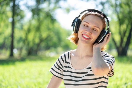 Young attractive woman listens to music in the park. Enjoying music in the park