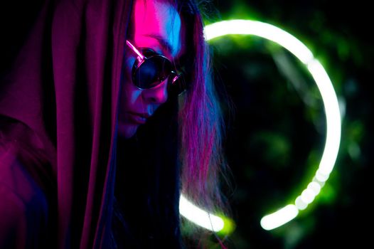 Portrait of asian man in hood and sunglasses in neon light