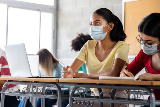 Teen latina girl wears protective face mask in high school class. Copy space. Education concept. Healthcare concept.