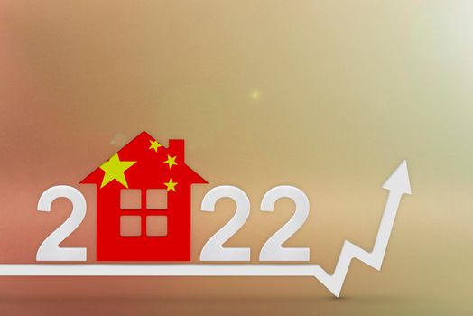 The cost of real estate in China in 2022. Rising cost of construction, insurance, rent in China. House model painted in the colors of the flag, up arrow on a red background.