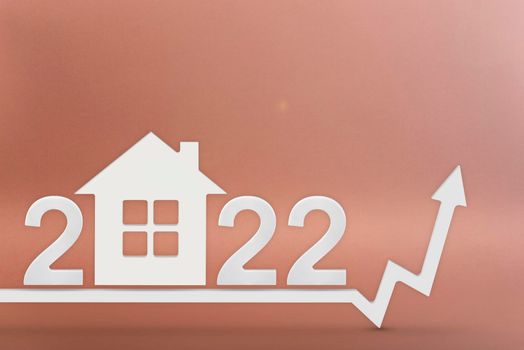 Real estate value in 2022. Rising costs of construction, insurance, rent and mortgages. inflation and rising prices. House model on a red background. Numbers 2022 on the up arrow