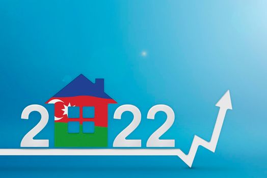 The cost of real estate in Azerbaijan in 2022. Rising cost of construction, insurance, rent in Azerbaijan. House model painted in the colors of the flag, up arrow on a blue background.