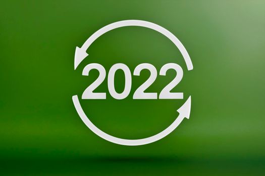 Ecology, recycling symbol 2022, white arrows form a circle. 3D image on a green background. Green products, green renewable energy, graph pointing up and down.