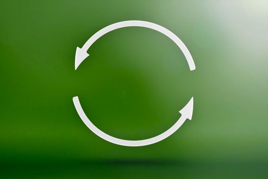 Ecology, recycling symbol, white arrows form a circle. 3D image on a green background. Green products, green renewable energy, graph pointing up and down.