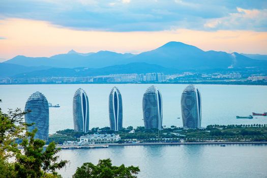 Evening skyscrapers on the sea bay with blue clouds