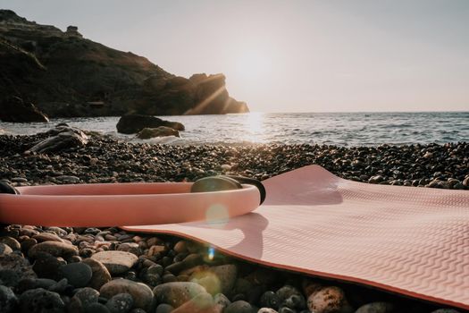 Young woman with long hair in white swimsuit and boho style braclets practicing outdoors on yoga mat by the sea on a sunset. Women's yoga fitness routine. Healthy lifestyle, harmony and meditation