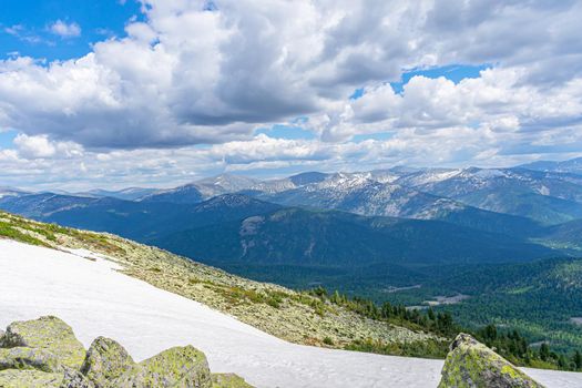 A view of the mountain range and snow-capped peaks with low flying clouds. Mountainous terrain and pure nature