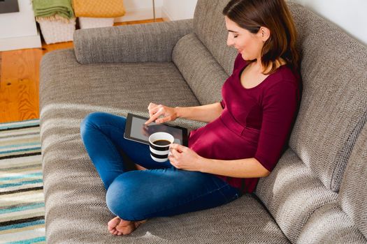 Beautiful woman at home in the sofa and working with a tablet