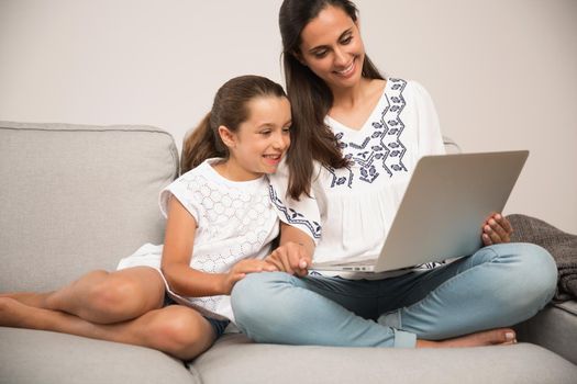 Mom teaching Daughter working with a a laptop at home9