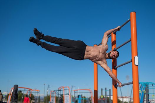 Shirtless man doing human flag outdoors