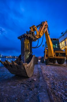 Big yellow stopped excavator at the construction site. Vertical view