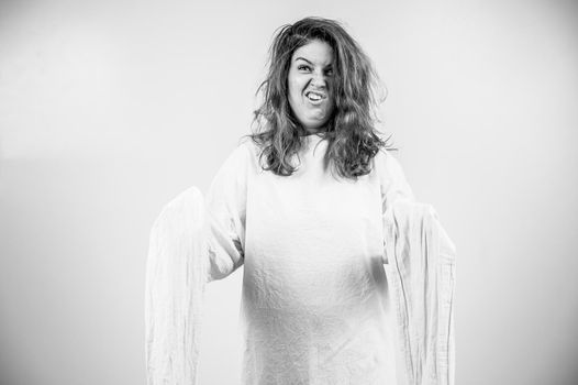 Close-up portrait of insane woman in straitjacket on white background. Monochrome