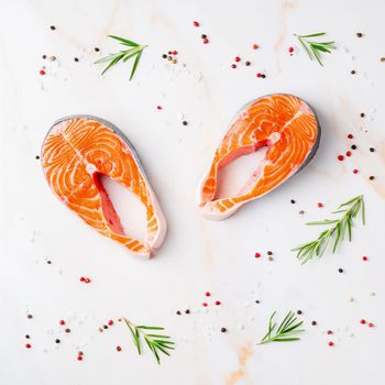 Food background, salmon steaks and seasonings on white cream marble table, flat lay.