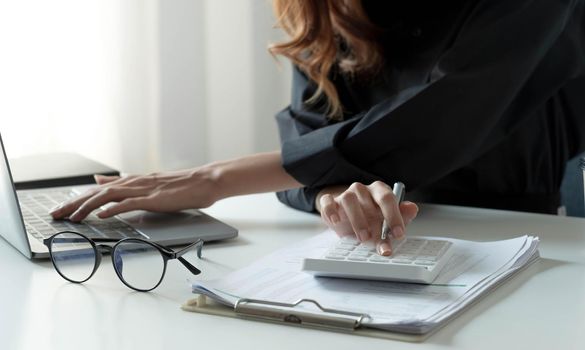 Close up Businessman using calculator and laptop for calaulating finance, tax, accounting, statistics and analytic research concept.