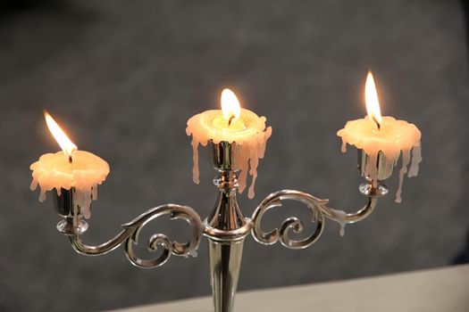 Vintage candlestick with three burning candles. Horizontal view.