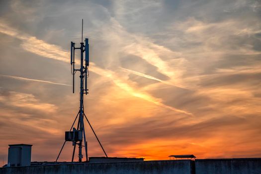 silhouette of GSM transmitters on the roof office building at amazing clouds