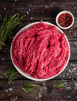 Mince beef, ground meat with ingredients for cooking on old gray dark wooden rustic table, top view, vertical