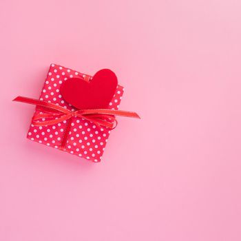 gift in red gift box with bow, red heart, pink background, top view, empty space for text
