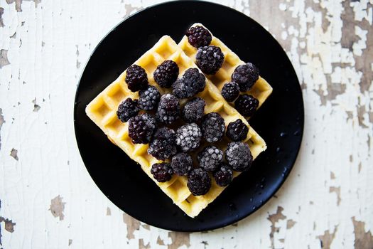 Belgian waffles with blackberry on an old wooden table.