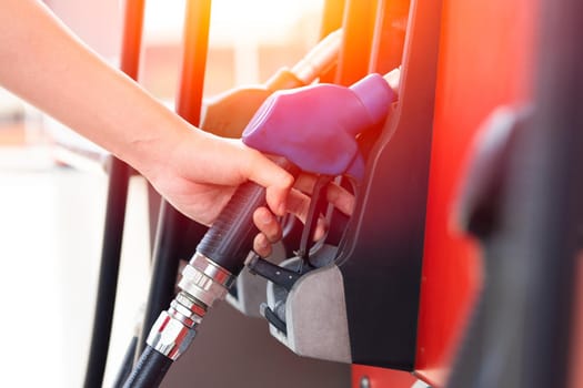 Worker hand at Gas station handle fuel nozzle at fuel dispensers for filling car engine gasoline