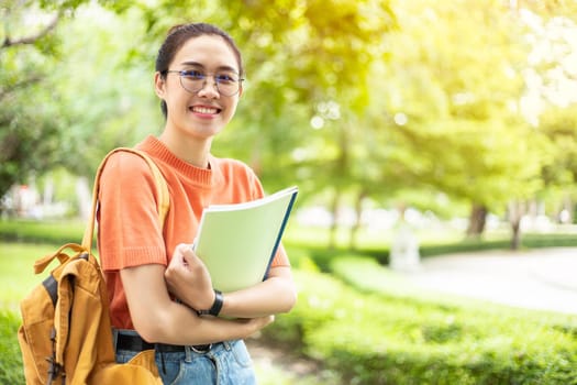 Portrait of nerd Asian woman girl smart teen happy smiling with glasses at green park outdoor in university campus with copyspace