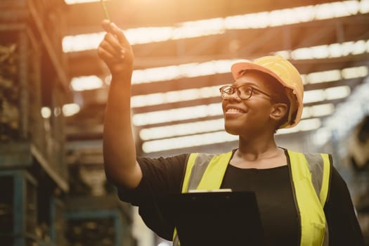 Black African professional women worker happy working count checking inventory production stock control in business factory  industry warehouse waring engineer suit and helmet for safety