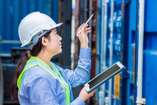Asian woman worker in warehouse using tablet computer to check cargo control goods order in inventory warehouse.