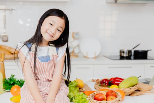 Portrait little cute girl child sitting on the table kitchen room background